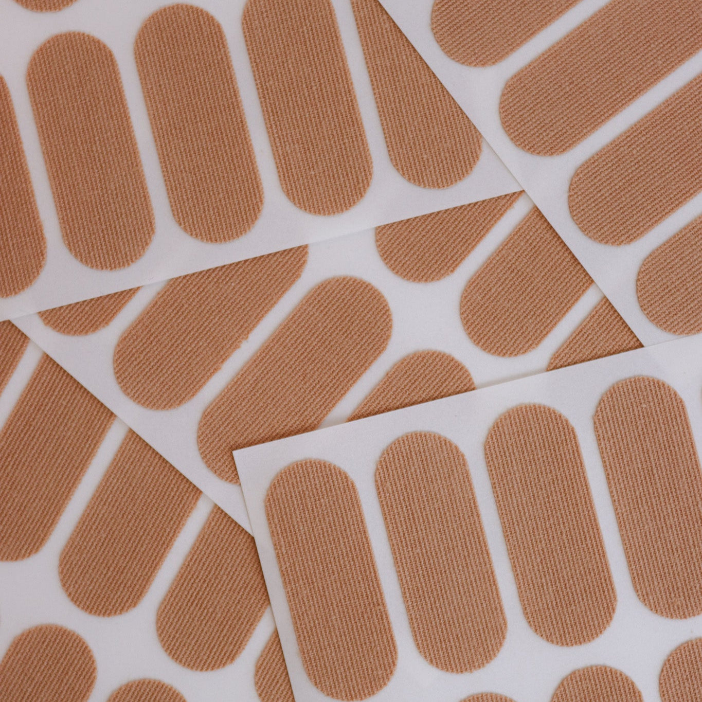 Multiple skin colored kinesiology face tape patches on a white background