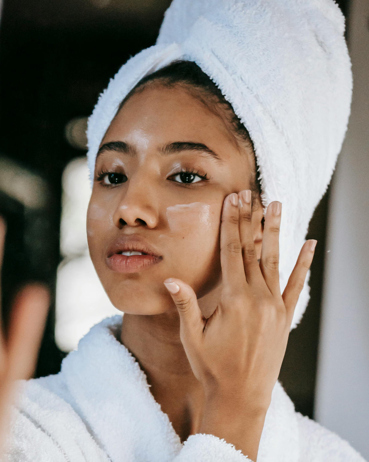 Woman applying skincare before face taping to hydrate and prep skin for optimal adhesion and results