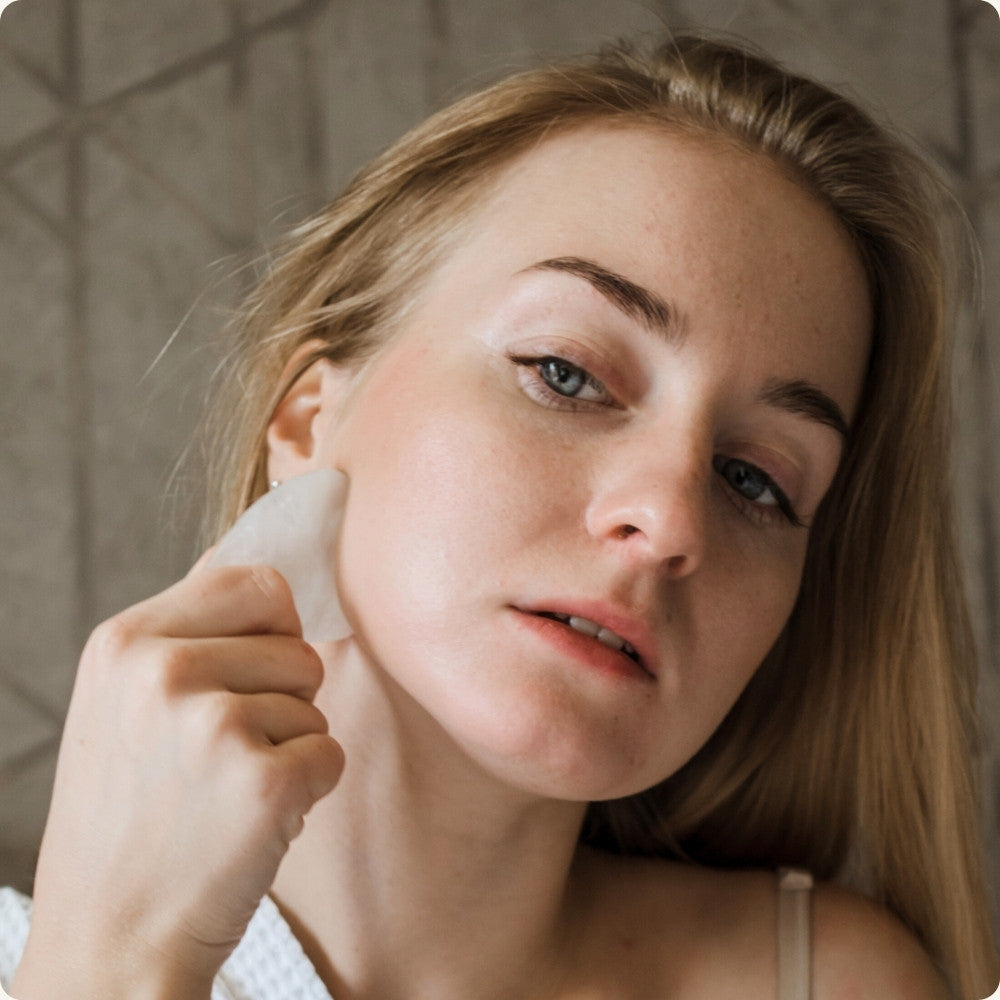 Woman performing facial massage using a gua sha