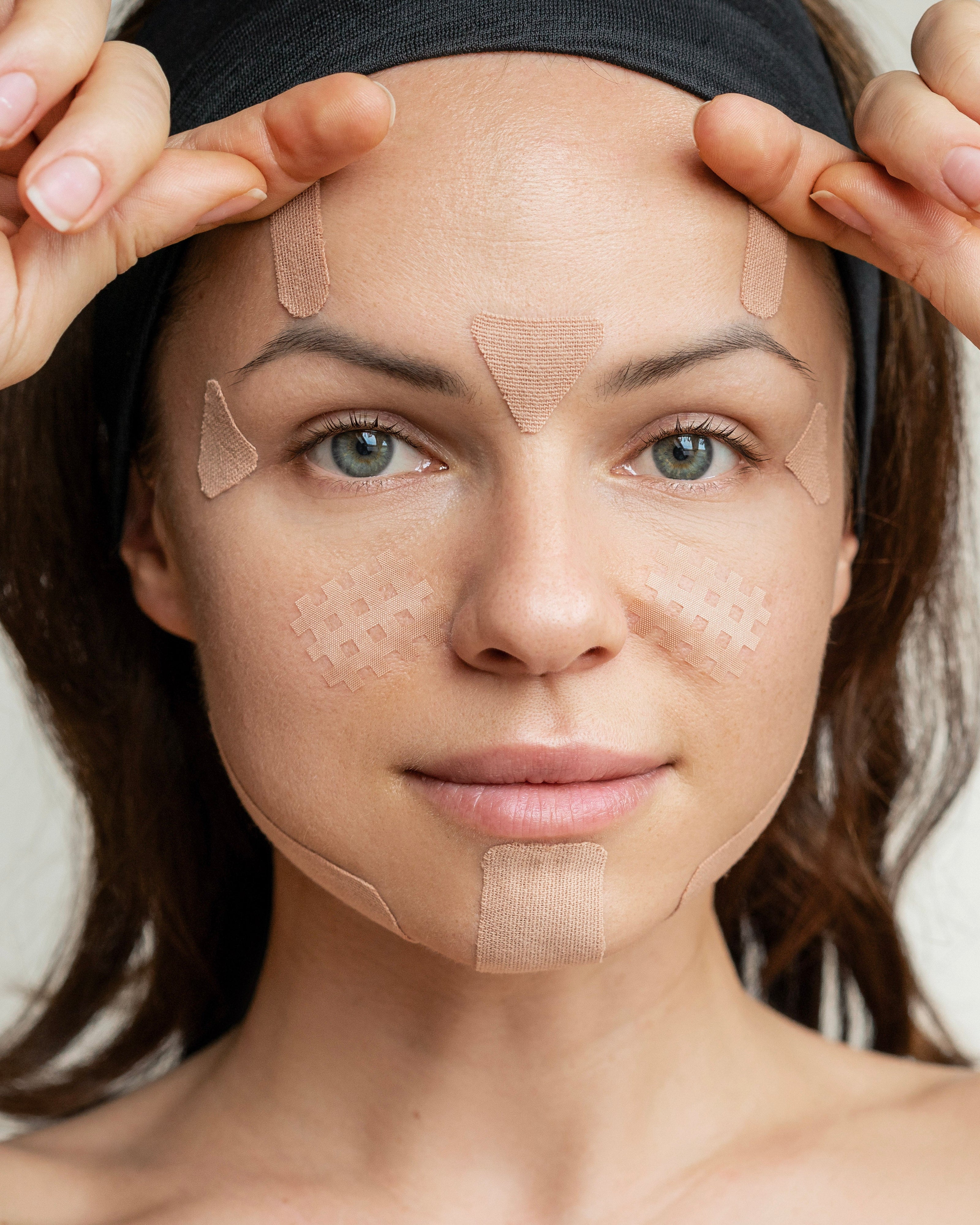 Woman wearing Holli kinesiology face tape to support circulation, reduce puffiness, and smooth fine lines overnight