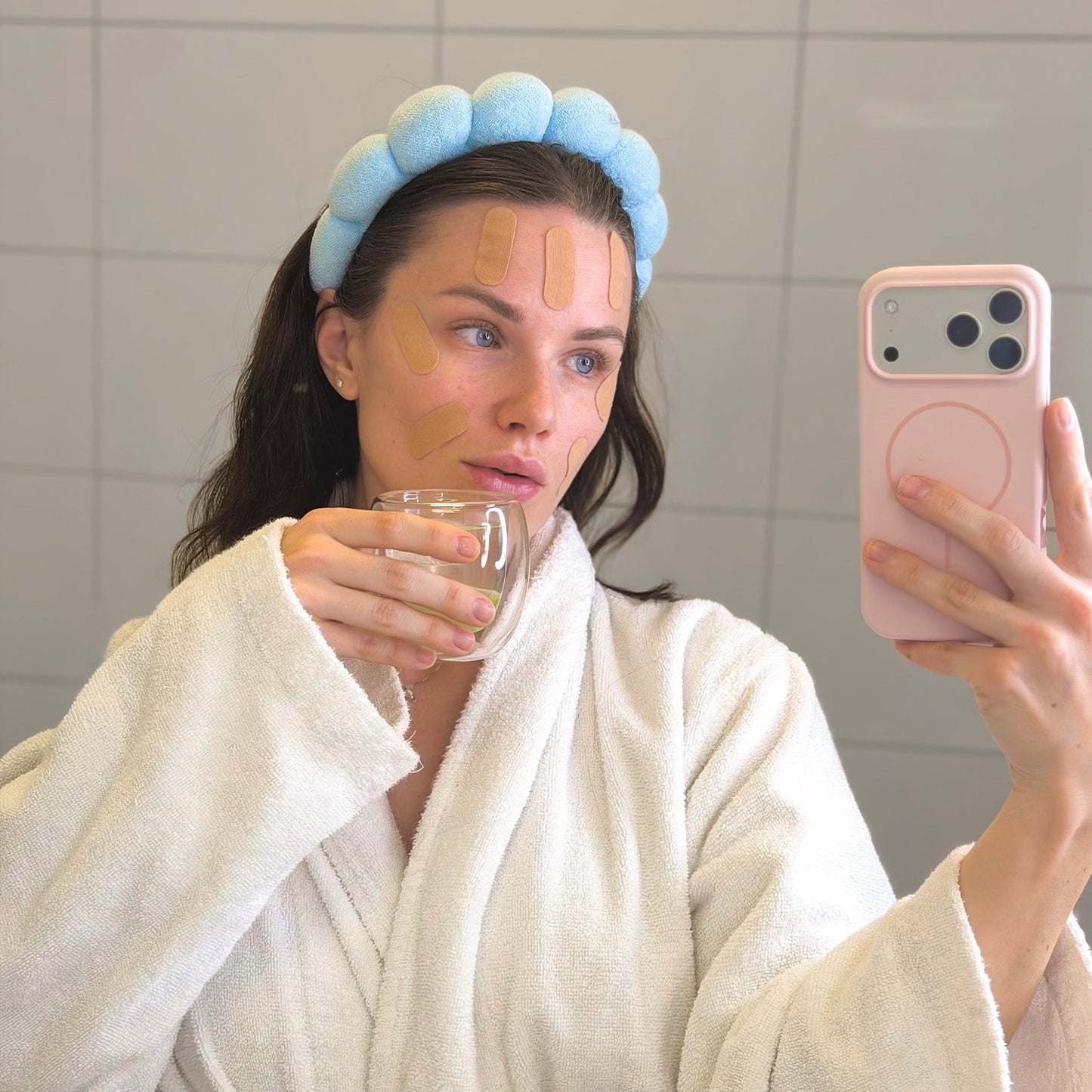 Woman taking mirror selfie wearing HOLLI pre-cut face tape